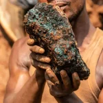 an artisanal miner, holds a cobalt stone at the Shabara artisanal mine