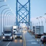 Commercial trucks and passenger vehicles drive across the Ambassador Bridge on the Canada-United States border in Windsor, Ont.